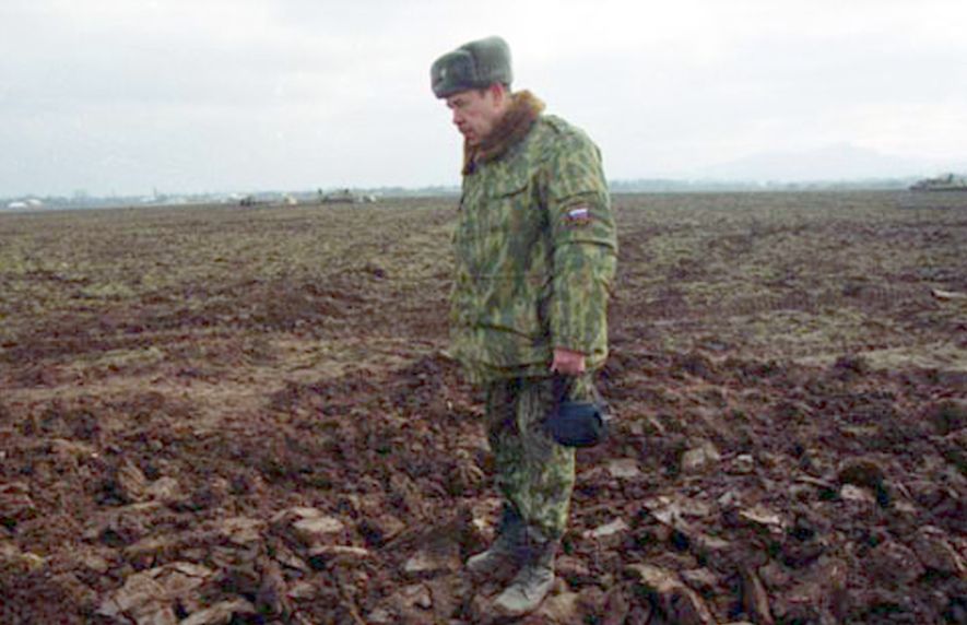 Rosyjski żołnierz stoi na masowym grobie Czeczenów. Spod ziemi wystają ich twarze. 2000 r.