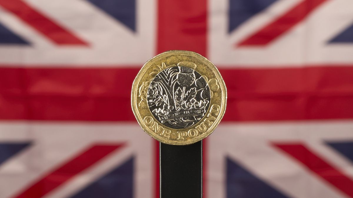 The image shows a close-up of a British one-pound coin with the Union Jack flag in the background. The photo symbolizes the United Kingdom's economy, national currency, and financial identity in the United Kingdom on October 10, 2025. (Photo by Matteo Della Torre/NurPhoto via Getty Images)