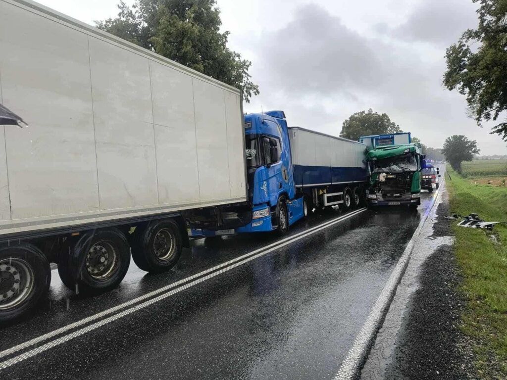 Zderzenie dwóch ciężarówek na mokrej drodze, w deszczowej aurze, z uszkodzoną kabiną jednej z nich.