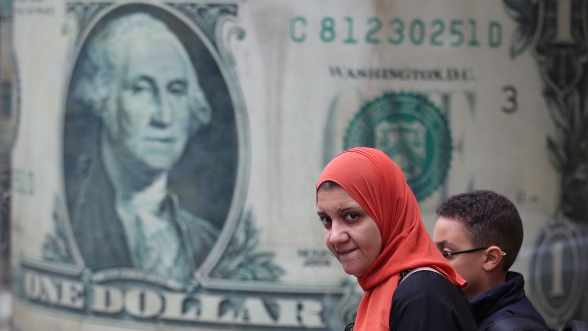 An Egyptian woman walks past a large-scale image of the US dollar banknote on a currency exchange office in Cairo, Egypt, 12 March 2024. Egypt is expecting a primary surplus of 3.5 percent in its GDP in the upcoming fiscal year 2024/2025, Minister of Finance Mohamed Maait said on 12 March, adding that the initial surplus as well as 50 percent of the IPO sales' revenues will be directed to reducing the government's debt. Egypt and the International Monetary Fund (IMF) had an agreement to extend a three billion USD loan deal to eight billion USD, following a massive deal with the United Arab Emirates for land-development projects worth 35 billion US dollars. EPA/KHALED ELFIQI Dostawca: PAP/EPA.