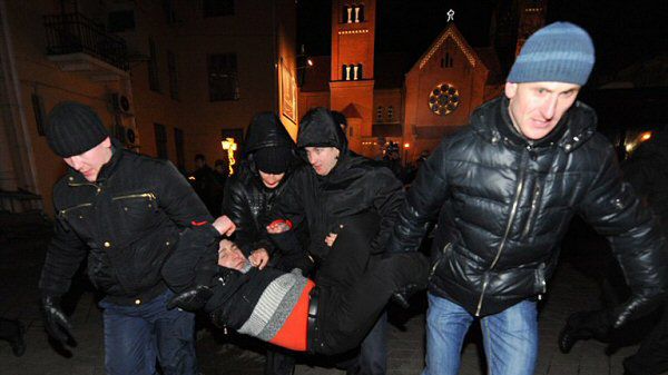 Milicjanci niosą zatrzymanego mężczyznę