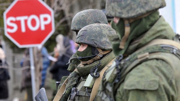 Uzbrojeni mężczyźni bez oznaczeń na mundurach blokują wejście do bazy ukraińskich sił w pobliżu Symferopola