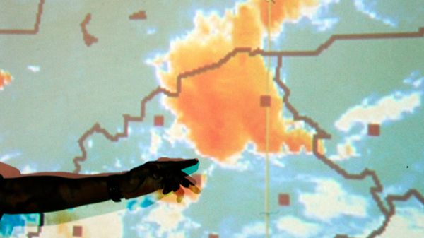 Mapa pogodowa przedstawiona przez centrum kryzysowe Burkina Faso - na pomarańczowo zaznaczono burze; postać wskazuje palcem miejsce, w którym samolot próbował zawrócić