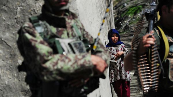 Mała Afganka obserwuje żołnierzy koło jej domu