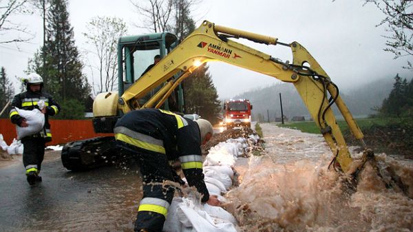 Strażacy układają worki z piaskiem, zabezpieczając zalaną drogę