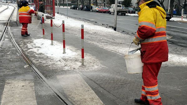 Pracownicy Tramwajów Warszawskich posypują chodniki solą