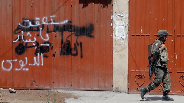 Libański żołnierz przechodzi obok graffiti wieszczącego upadek prezydenta Syrii; libański Trypolis