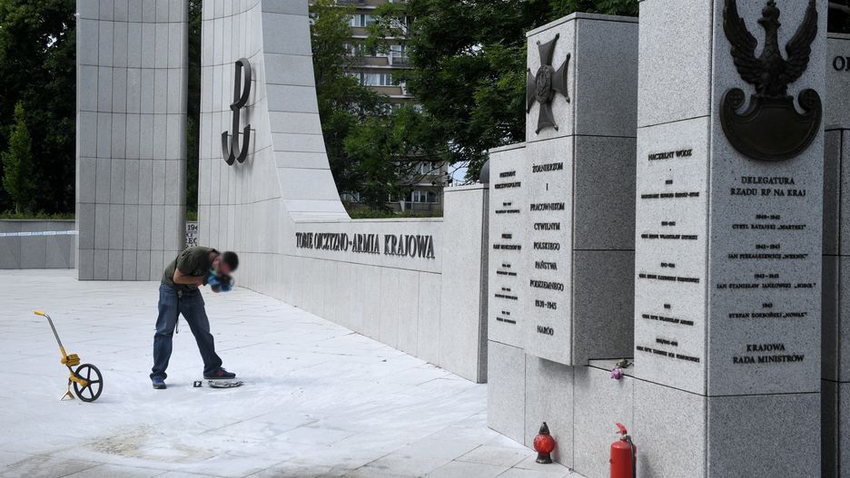 Policyjny technik zbiera dokumentację w miejscu, w którym doszło do samopodpalenia