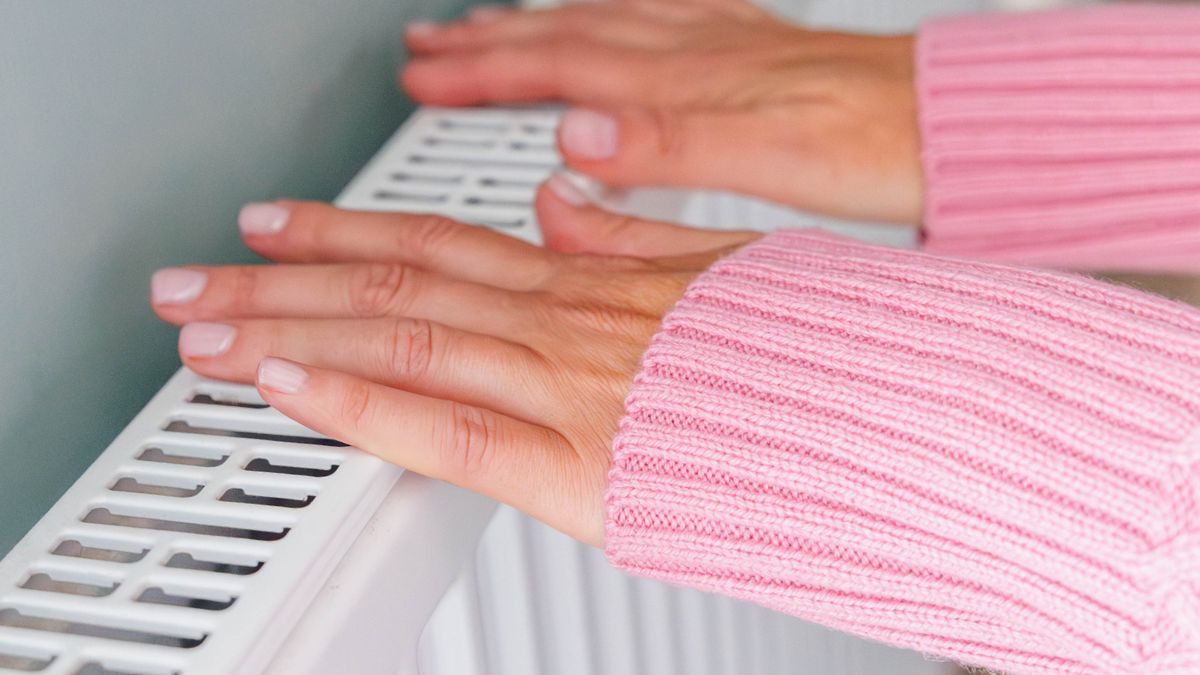 Kobieta trzyma dłonie na kaloryferze