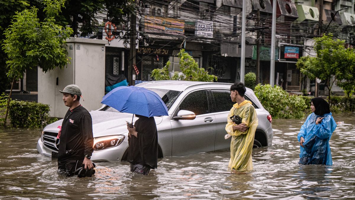 BANGKOK, THAILAND - SEPTEMBER 26: People walk through floodwater on a road as a car is submerged in floodwater during heavy rain in Bangkok, Thailand, on September 26, 2026. The Thai Meteorological Department issues a warning for heavy to very heavy rain in Greater Bangkok and other provinces across Thailand. (Photo by Wissarut Weerasopon/Anadolu via Getty Images)