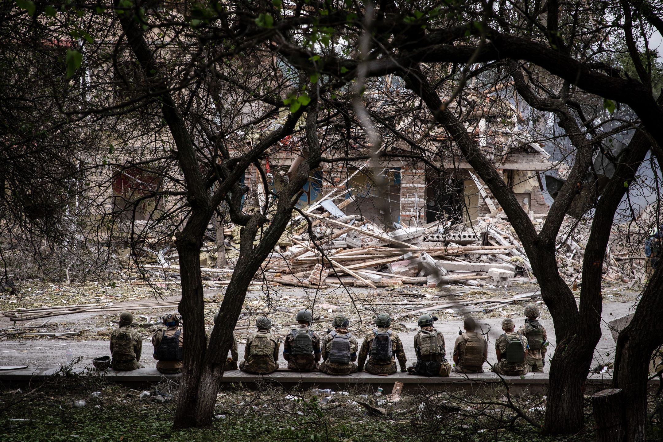 KRAMATORSK, DONETSK, UKRAINE - 2022/07/21: Ukrainian soldiers are sitting at the shelling scene of a destroyed school in Kramatorsk. As Russia stepped up its "military operation" in Ukraine, a school in Kramatorsk was hit and destroyed by Russian rockets on July 21. Ukrainian officials claimed they had discovered at least three bodies. Kramatorsk, a strategic railway hub city of more than 150,000 people before the Russian invasion, will more likely become the main focus of the Russian forces in the east. (Photo by Alex Chan Tsz Yuk/SOPA Images/LightRocket via Getty Images)