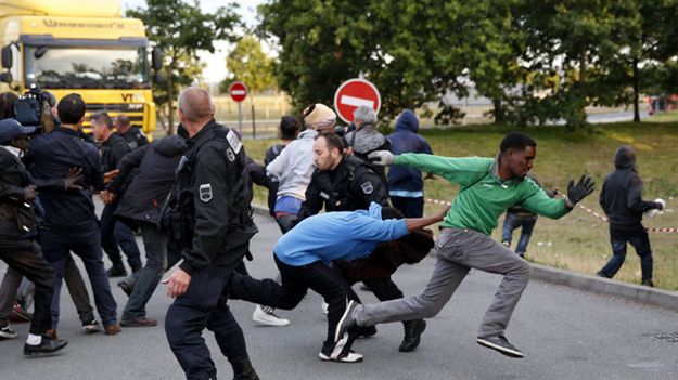 Imigranci uciekają przed francuską policją, by dostać się do pociągu jadącego do Wielkiej Brytanii - Calais, 30 lipca