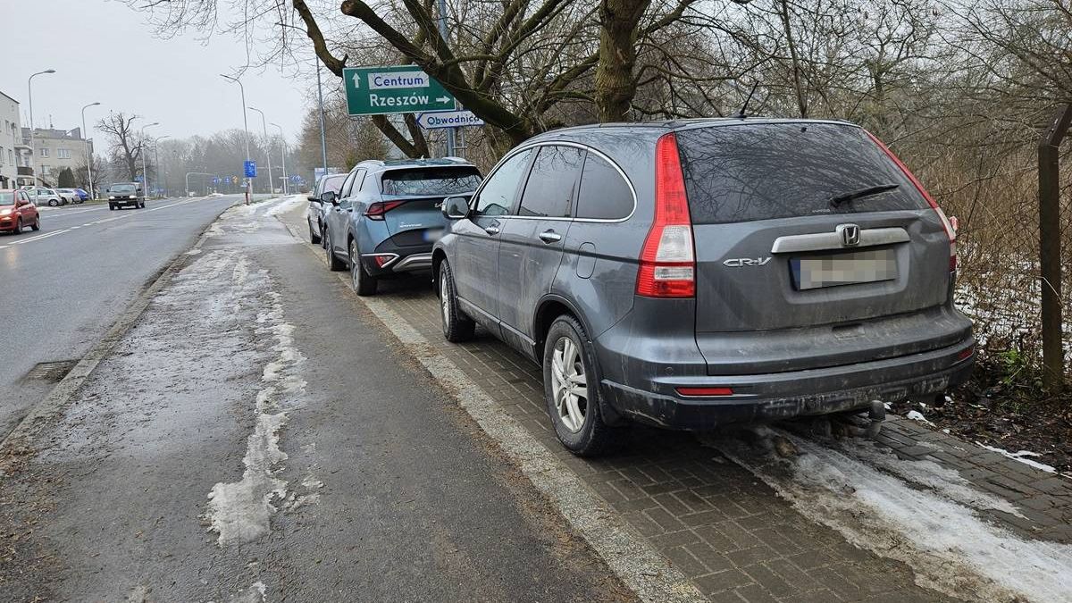 Samochody zaparkowane na chodniku na al. Warszawskiej