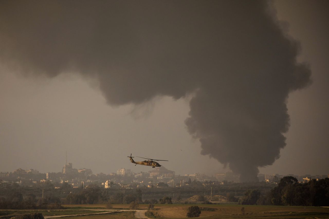 An Israeli helicopter is flying along the border. Smoke is rising from the Gaza Strip.
