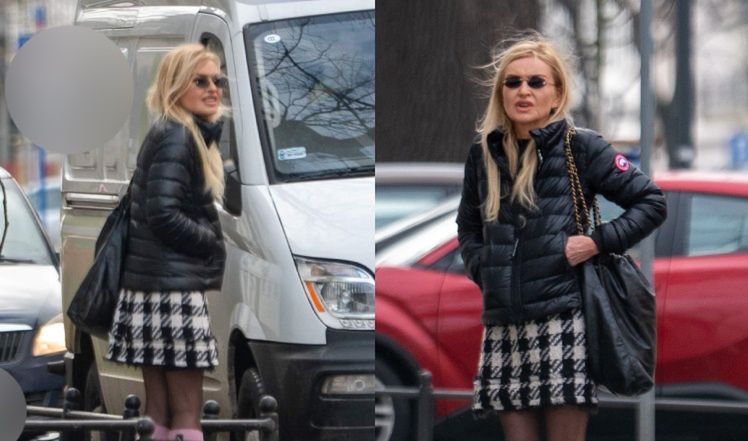 
Monika Olejnik w krótkiej spódnicy czeka przy ulicy z walizkami