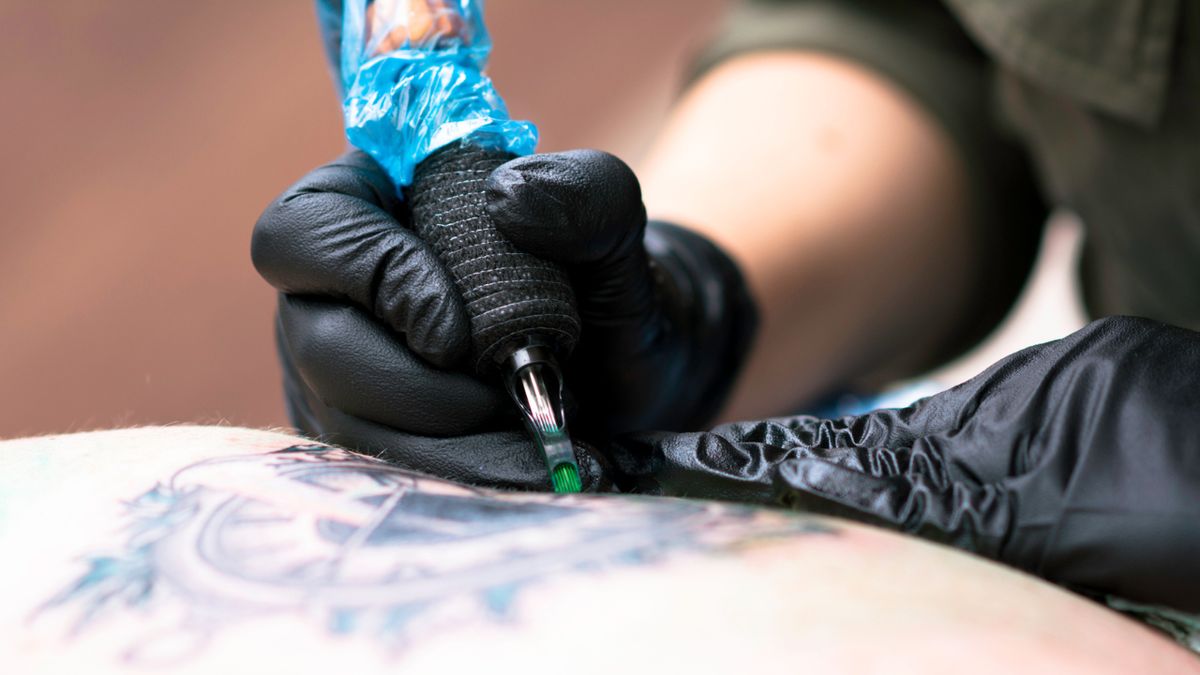 Zbliżenie na dłoń tatuatora wykonującego tatuaż