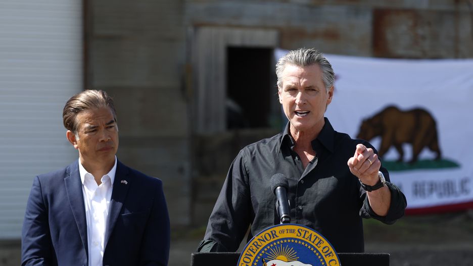 CERES, CALIFORNIA - APRIL 16: California Governor Gavin Newsom (R) speaks as  California Attorney general Rob Bonta looks on during a news conference at Gemperle Orchard on April 16, 2025 in Ceres, California. Governor Gavin Newsom and California Attorney General Rob Bonta have filed a lawsuit in federal court challenging the Trump administration's use of emergency powers to enact sweeping tariffs that hurt states, consumers, and businesses. The tariffs have disrupted supply chains, increased costs for the state and Californians, and inflicted billions in damages on California’s economy, the fifth largest in the world. (Photo by Justin Sullivan/Getty Images)