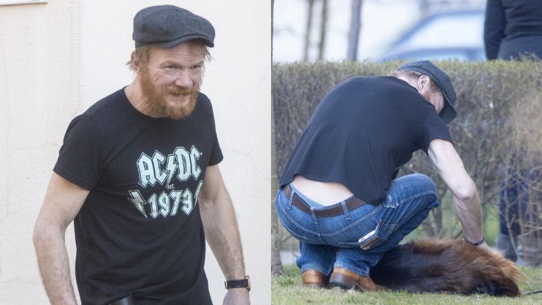 Zarośnięty Eryk Lubos bawi się z psem