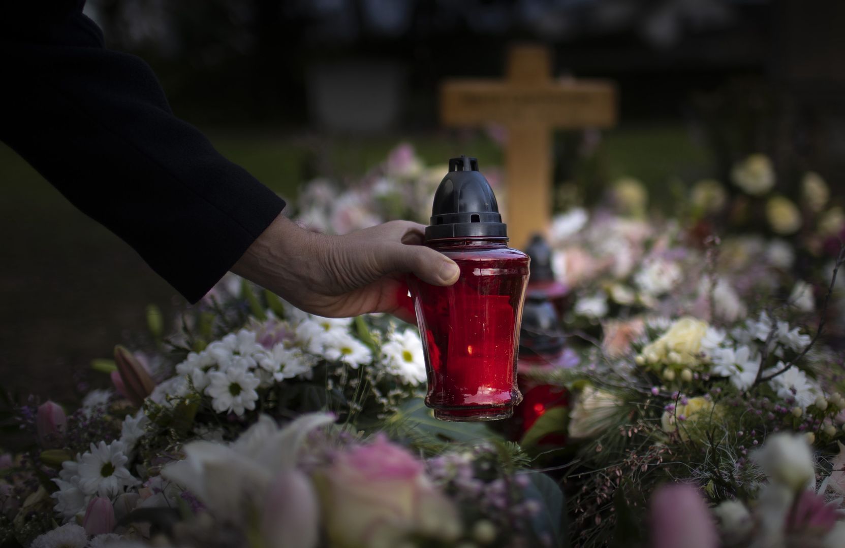 Cemetery, farewell,Bonn, Germany - January 21:  In this photo illustration a man puts a grave light on a grave on January 21, 2021 in Bonn, Germany. (Photo by Ute Grabowsky/Photothek via Getty Images)Ute Grabowskysymbolfoto, symbolbild, symbol picture symbol image, symbole, symbolisch, symbols, symbolic, creative, featurethemen, gesundheit, health, medizin, corona, uebersteblichkeit, friedhof, friedhoefe, cemeteries, christentum, abschied, sterben, tod, grab, begraebnis, trauer, trauern, grablicht, grablampe, grableuchte, kerze, blumen, kreuz, farewell, dying, burial, grieving, supernatural, grave light, grave lamp, flowers, cross