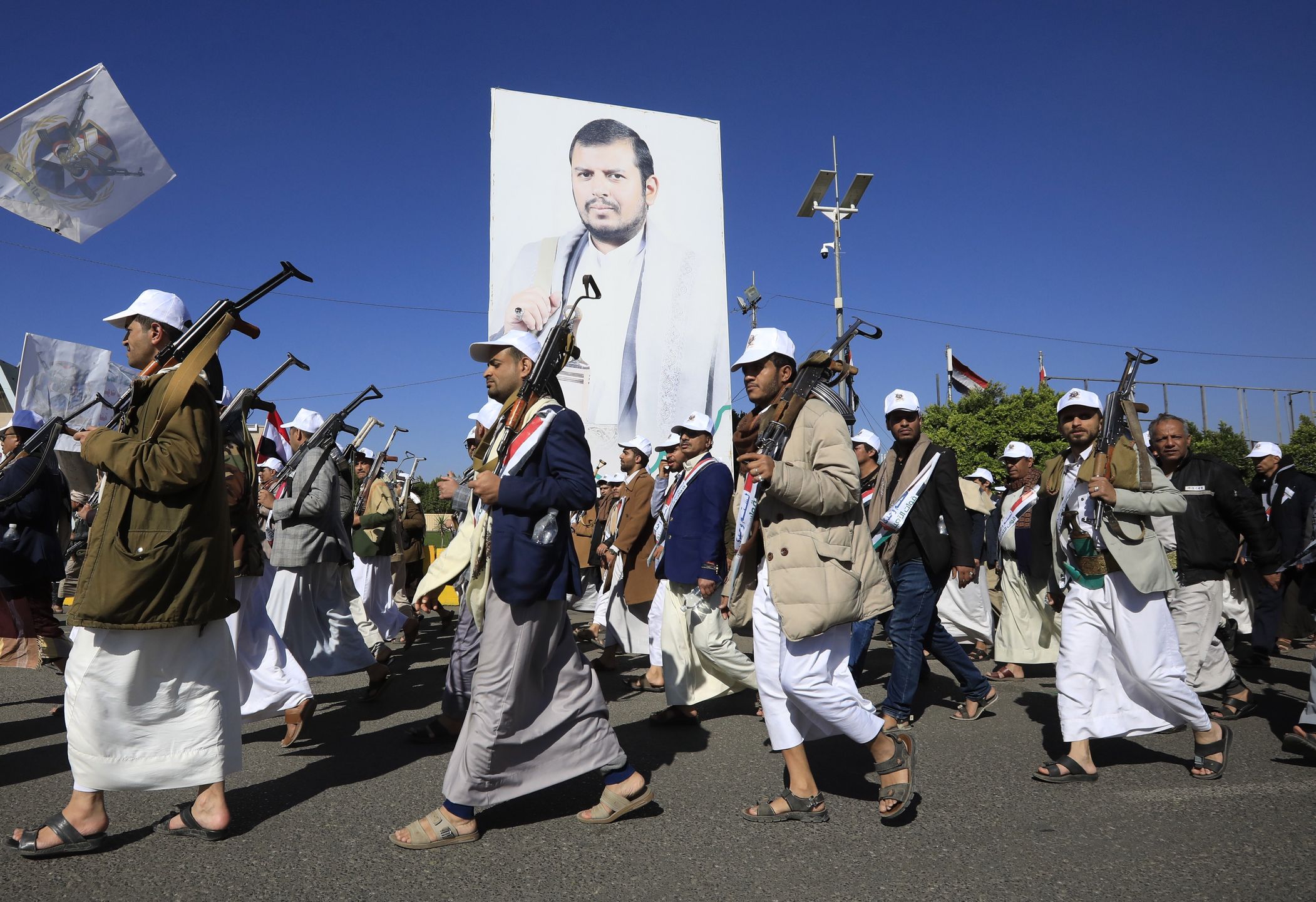 Nowo zrekrutowani członkowie popularnej armii Huti maszerują obok dużego sztandaru przedstawiającego najwyższego przywódcę Abdula-Malika al-Houthi podczas parady w Sanie