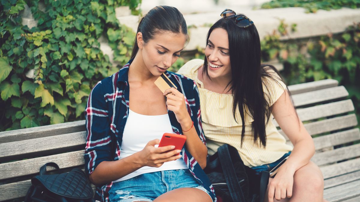 Young women in the city park using smartphone for online shopping