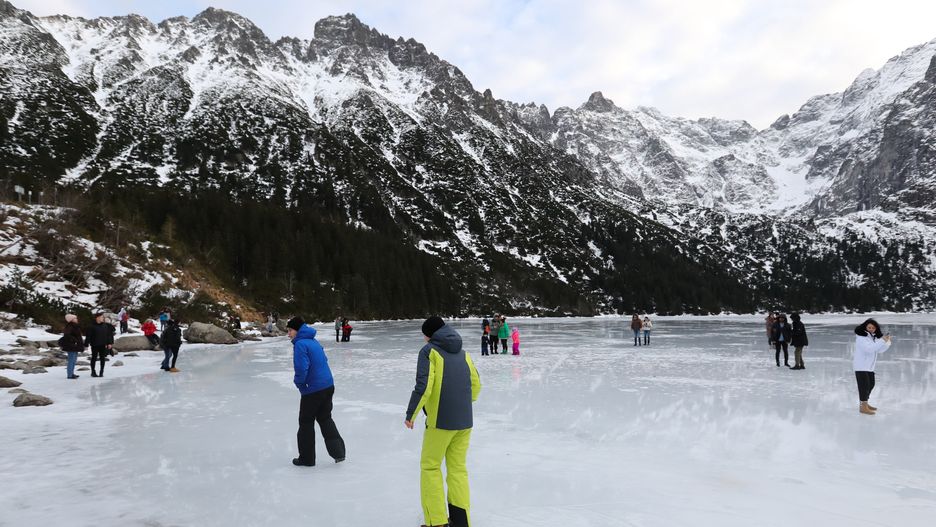 Tatry, Morskie Oko, 26.12.2022. Turyści na tafli lodu na jeziorze Morskie Oko w Tatrach, 26 bm. Tatrzański Park Narodowy ostrzega przed wchodzeniem na zamarznięte górskie jeziora � z powodu panujących w ciągu dnia dodatnich temperatur lód jest bardzo cienki i grozi załamaniem. (jm) PAP/Grzegorz Momot
