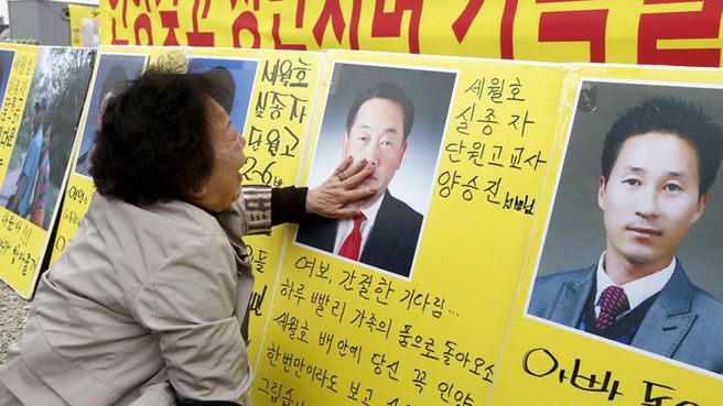 Matka nauczyciela, który zginął w katastrofie, przed portretem syna