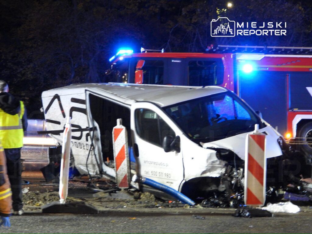 Samochód dostawczy zniszczony w wypadku, otoczony przez służby ratunkowe i znaki drogowe, w nocy na drodze.
