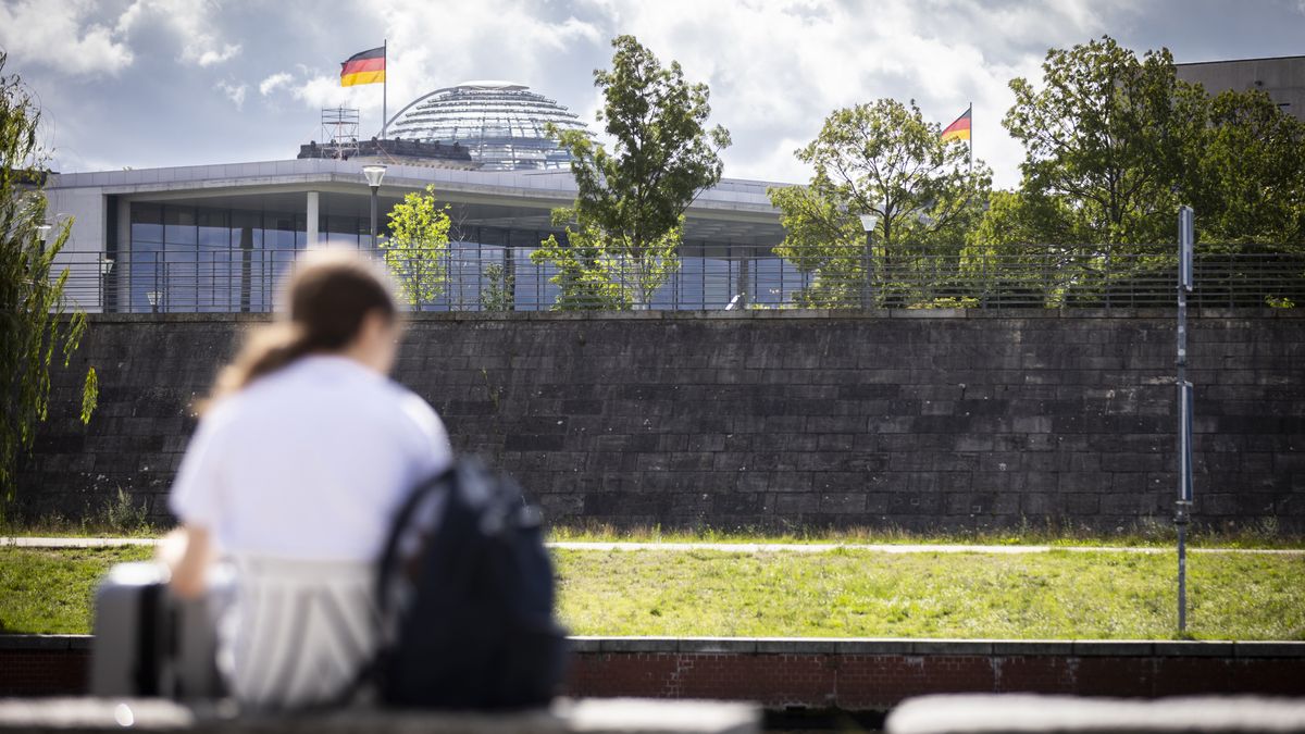 BERLIN, GERMANY - JULY 30: In this photo illustration a tourist is sitting at the Spree river near the Reichstag in Berlin with her luggage on July 30, 2025 in Berlin, Germany. (Photo Illustration by Amrei Schulz/Getty Images)
