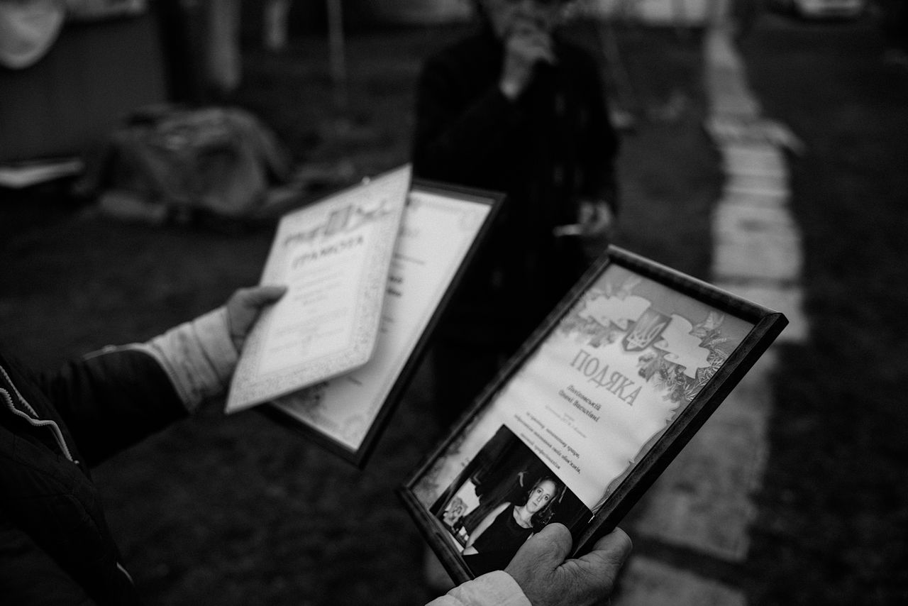 Nina shows Lena’s picture and diplomas