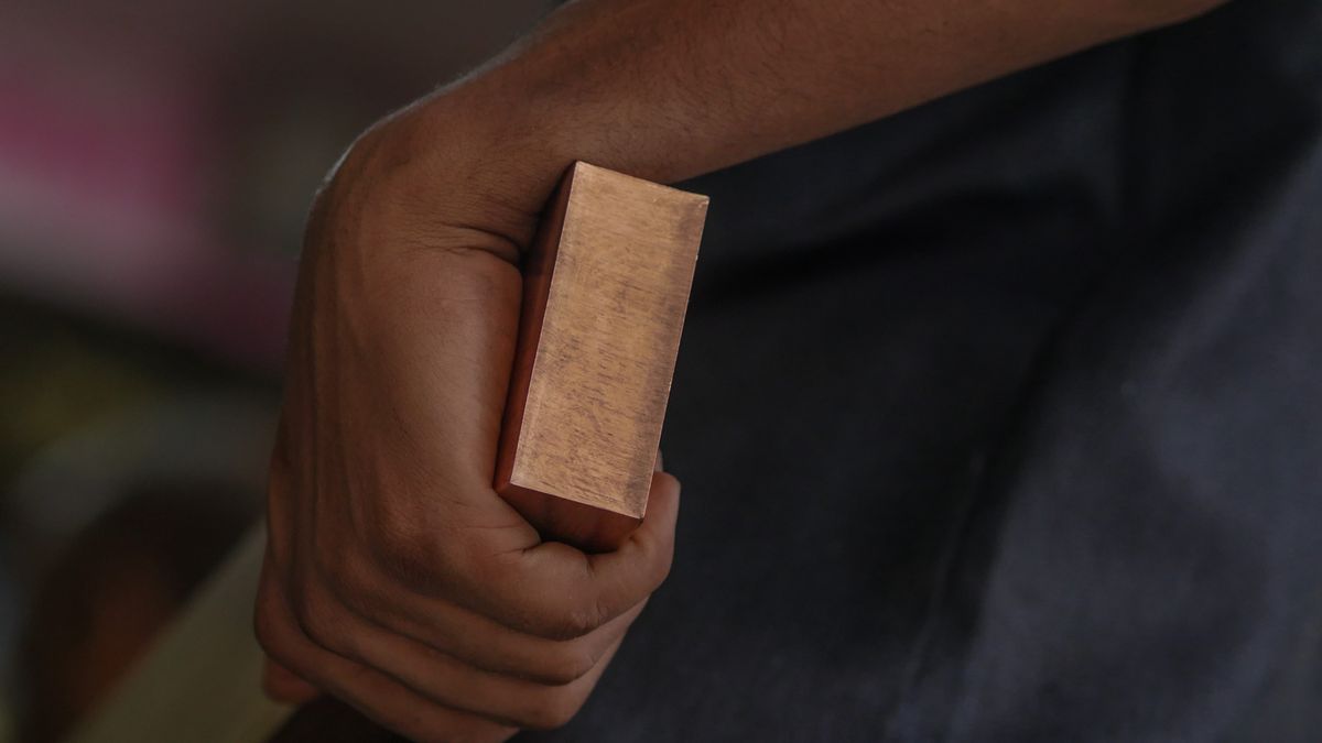 A worker holds a copper bar at a wholesale metal dealer in Mumbai, India, on Saturday, April 27, 2024. Copper hit $10,000 a ton for the first time in two years as speculation builds that the world's mines will struggle to meet a coming wave of demand from green industries. Photographer: Dhiraj Singh/Bloomberg via Getty Images