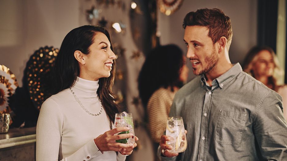 Dwoje ludzi rozmawia i trzyma napój podczas imprezy. -tytułowa