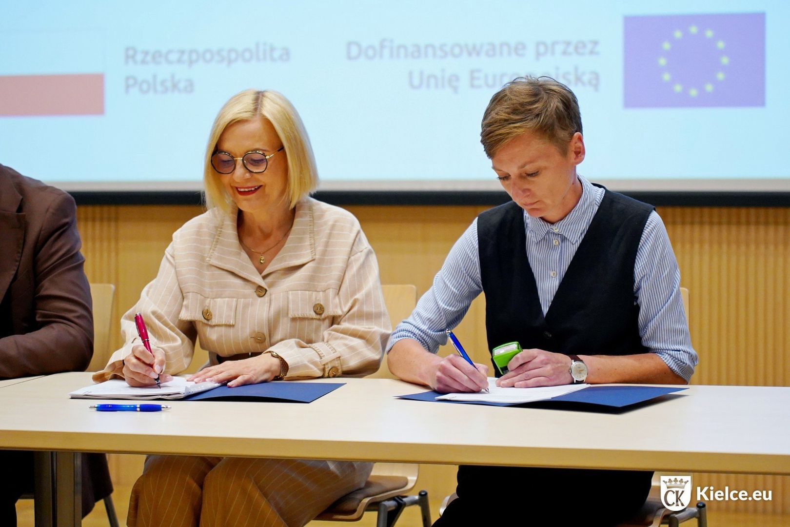 Projekt „Zeroemisyjny transport publiczny w centrum Kielc&#34; otrzymał ponad 12,5 mln zł dofinansowania z EFRR. Miasto zakupi pięć autobusów elektrycznych z infrastrukturą ładowania oraz utworzy siedem nowych przystanków. Nowe linie obsłużą dotychczas nieobsługiwane rejony, w tym ulice centrum (Czerwonego Krzyża, Wesoła, Św. Leonarda) i obszary osiedlowe (Śląska, Leszczyńska, Mielczarskiego). Na zdjęciu pani marszałek i pani prezydentka.
