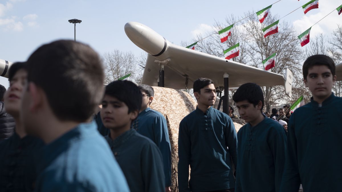 Iranian youth are standing under an Iranian-made unmanned aerial vehicle (UAV) Shahed-136, during a rally to mark the 44th anniversary of the Victory of Iran's 1979 Islamic Revolution, at Azadi (Freedom) Square in the west of Tehran on February 11, 2023. (Photo by Morteza Nikoubazl/NurPhoto via Getty Images)