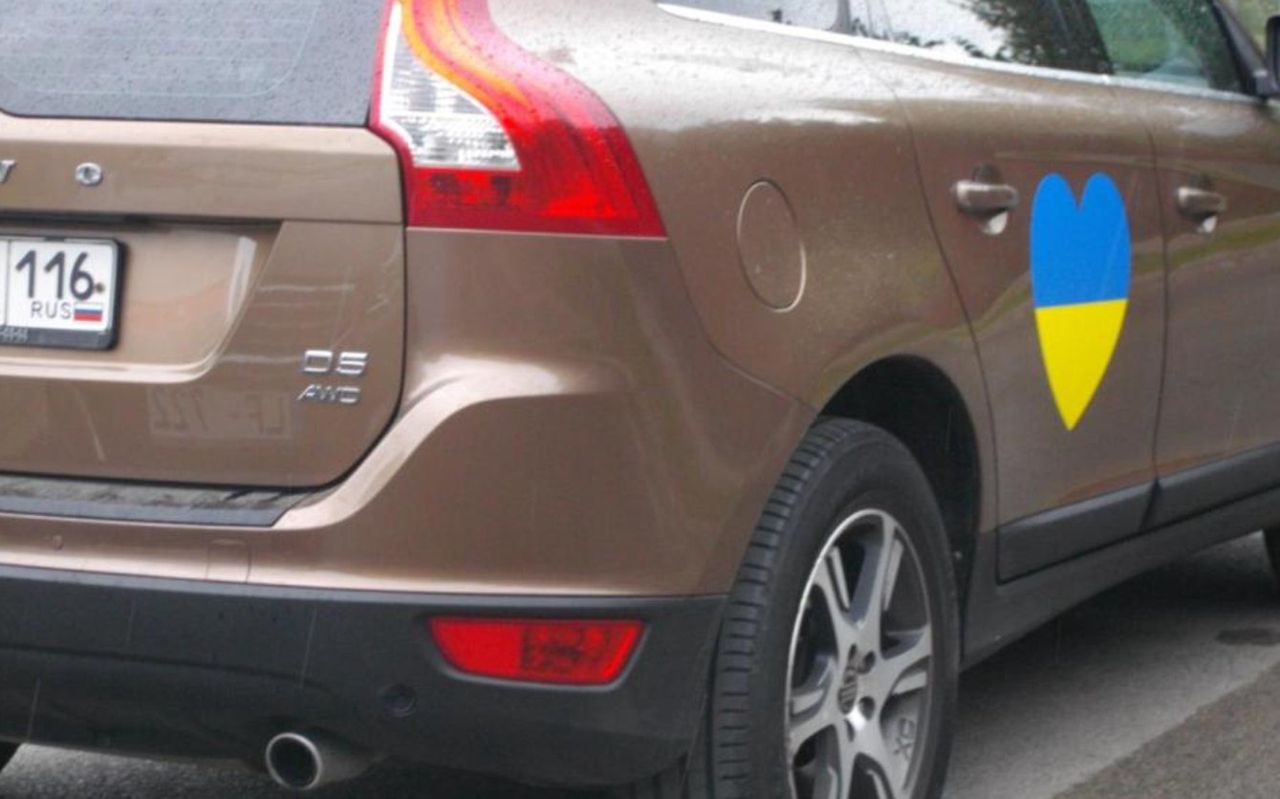 A car with Russian license plates with a symbol of solidarity with Ukraine