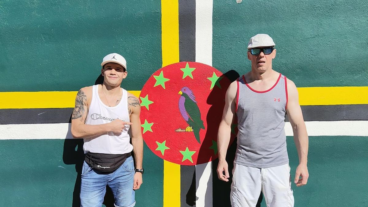 Filip Wąchała ze swoim trenerem Markiem Chrobakiem na tle flagi Dominiki