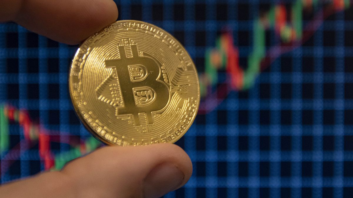 NETHERLANDS - 2020/12/22: In this photo illustration, the Bitcoin golden cryptocurrency commemorative coin seen displayed in front of uptrend graph lines. (Photo Illustration by Nik Oiko/SOPA Images/LightRocket via Getty Images)