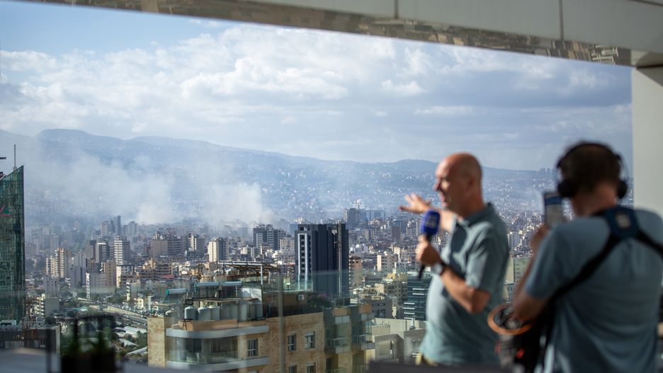 BEIRUT, LEBANON - OCTOBER 2: Broadcast journalists record as smoke rises from Israeli airstrikes that hit the city's southern suburbs early in the morning on October 2, 2024 in Beirut, Lebanon. After escalating strikes against Hezbollah facilities and leadership, the Israeli army announced it was launching a "limited" ground invasion of Lebanon and told residents of more than two dozen villages in the southern part of the country to evacuate. (Photo by Daniel Carde/Getty Images)
