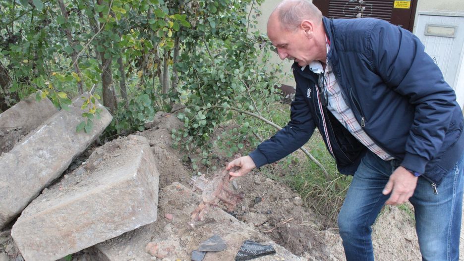 Krzysztof Krawczak, jeden z protestujących mieszkańców i radny Gminy Biesiekierz, pokazuje fragmenty nagrobków, które zebrał z terenu dawnego cmentarza w Nowych Bielicach.