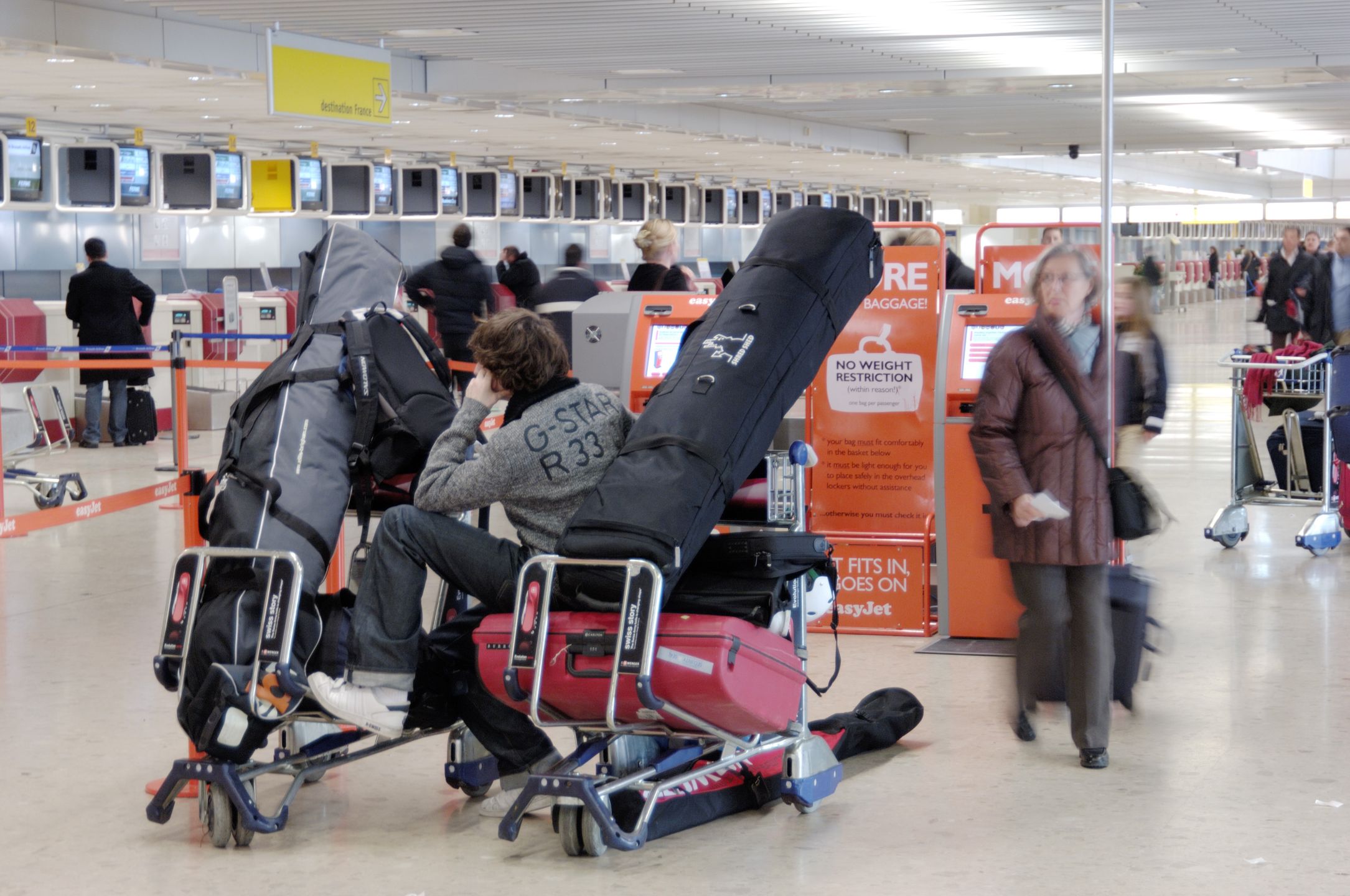 a man sitting on a baggage trolley full of luggage and skis in the easyJet check-in area
a man sitting on a baggage trolley full of luggage and skis in the easyJet check-in area. (Photo by: aviation-images.com/Universal Images Group via Getty Images)
aviation-images.com
airports, insides, interiors, internal, views, terminals, terminal, buildings, bags, suitcases, cases, baggages, checkin, check, in, checking, checking-in, check-ins, check-in, checkins, easy, jet, easy-jet, cost, airlines, carriers, low-cost, low-fare, baggage, gentleman, gentlemen, passengers, customers, seats, chairs, seating, seated, trolleys, trollies, carts