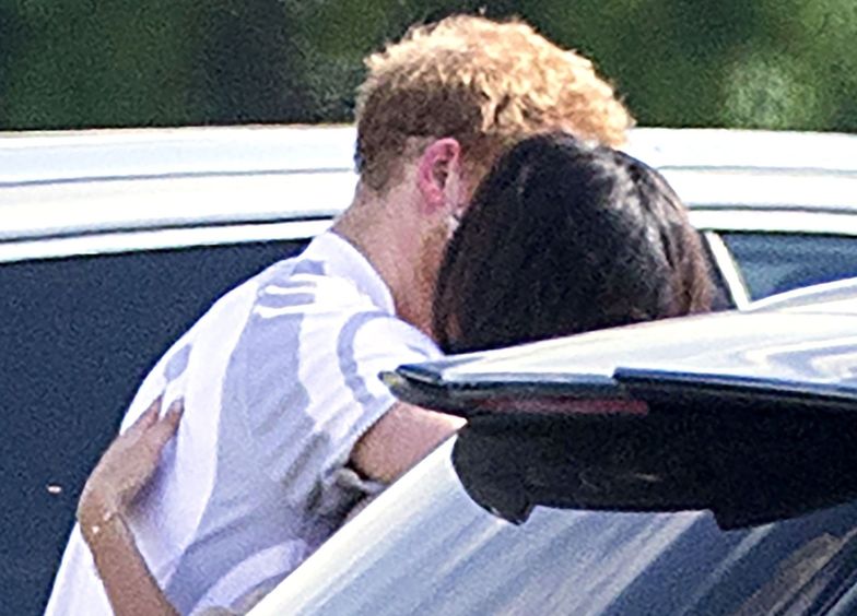 Książę Harry całuje się z Meghan Markle po meczu