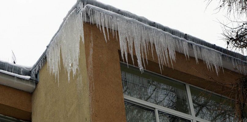 Zwisające sople i śnieg na dachach