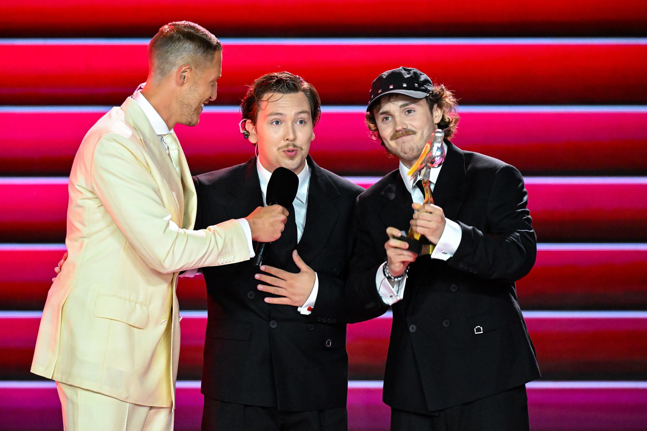 Sopot, 25.08.2026. Prowadzący Damian Michałowski (L) oraz Jakub Mieczaj (C) i Jakub Frankowski (L) z zespołu Kuba i Kuba odbiearają nagrodę w konkursie o Bursztynowego Słowika w drugim dniu Top of The Top Sopot Festival 2026 w Operze Leśnej w Sopocie, 25 bm. (sko) PAP/Andrzej Jackowski