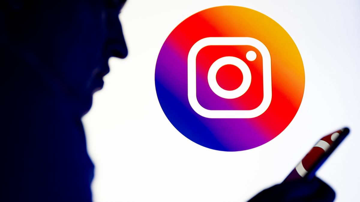 POLAND - 2025/11/26: In this photo illustration, a silhouetted individual is seen holding a mobile phone with an Instagram logo displayed in the background. (Photo Illustration by Mateusz Slodkowski/SOPA Images/LightRocket via Getty Images)