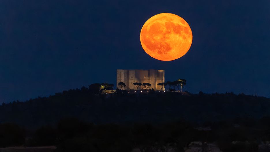 The full moon rises behind Castel del Monte in Andria, Italy, on August 9, 2025. The full moon in Aquarius is also known as the Sturgeon Moon. This name is linked to Native American traditions, particularly because they fish for sturgeon during this period. (Photo by Davide Pischettola/NurPhoto via Getty Images)