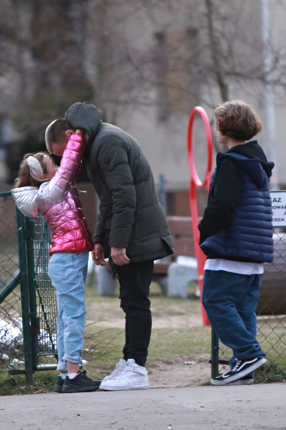 Marcin Hakiel dokazuje z dziećmi na placu zabaw