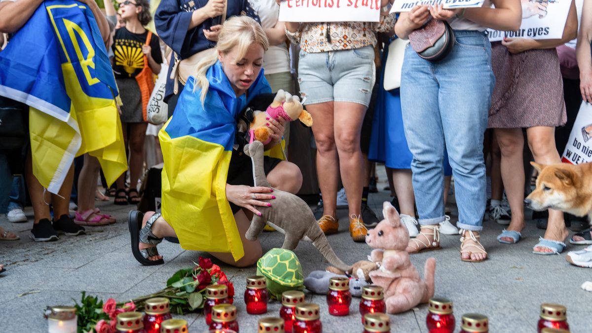 WARSAW, POLAND - 2024/07/09: A woman wrapped in the Ukrainian flag places toys in honor of the children who died in the attack on the children's hospital in Kyiv during the demonstration. On July 9, the day after the Russian bombing of Okhmatdyt Children's Hospital, several hundreds of people gathered to protest against the attacks on hospitals in Ukraine. In their speeches, the protesters confirmed that it was a Russian missile and not - as Russian propaganda claims - a Ukrainian anti-aircraft missile. In their speeches, the protesters also called for NATO to close the sky over Ukraine and for the UN to do more instead of talking. (Photo by Marek Antoni Iwanczuk/SOPA Images/LightRocket via Getty Images)
