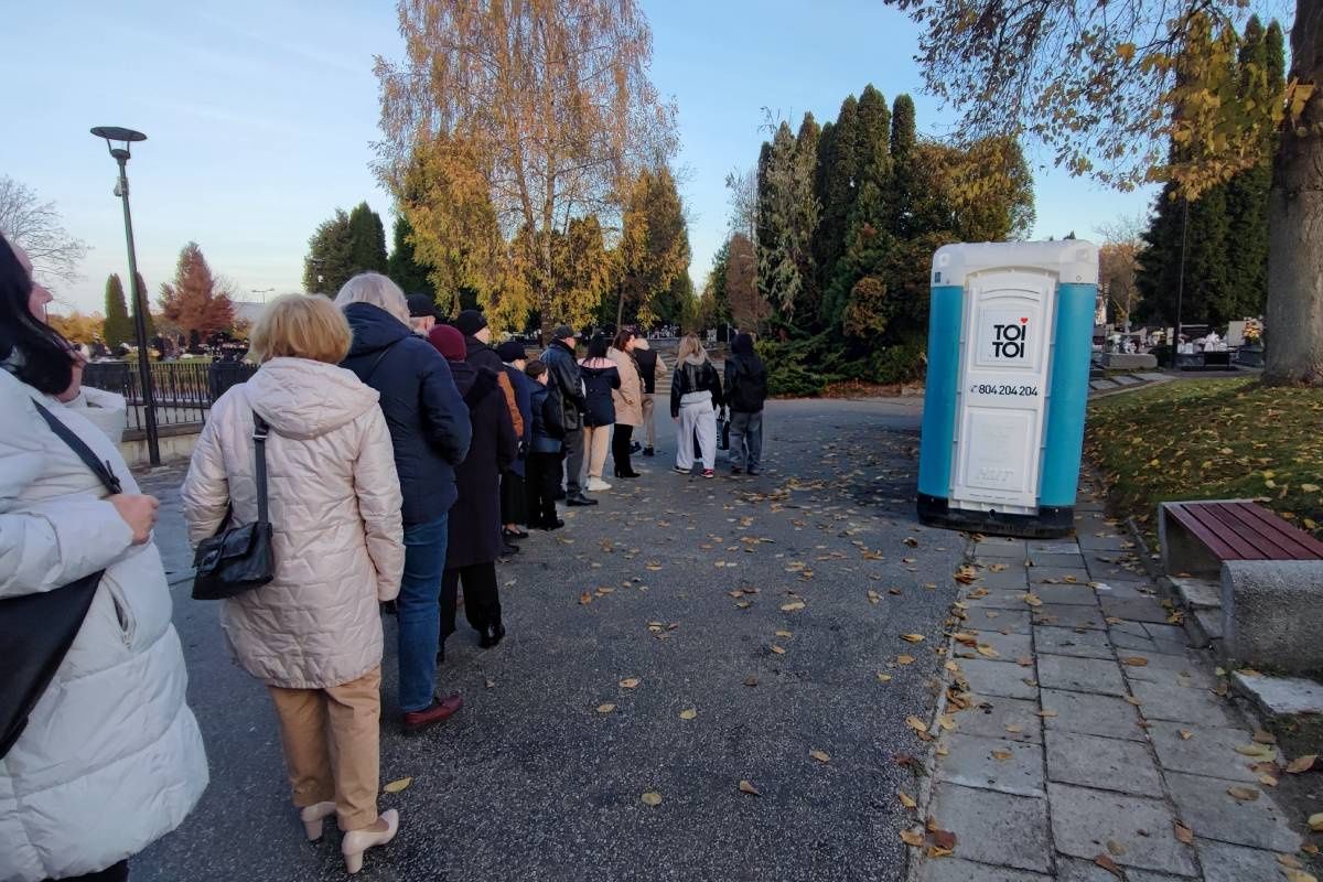 Ludzie oczekujący w kolejce do toi toi na cmentarzu na Majdanku