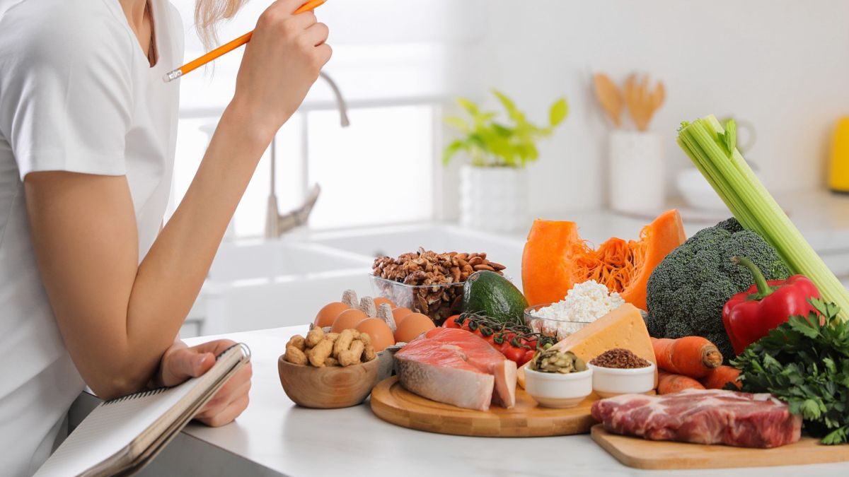 Kobieta z notesem i ołówkiem wśród zdrowych produktów