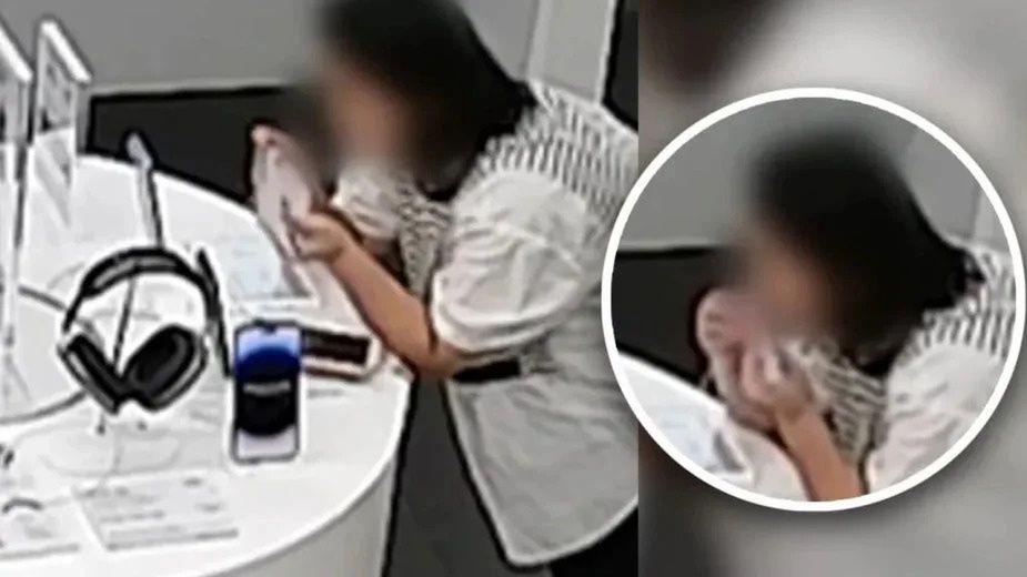 Kobieta przegryzająca linkę zabezpieczającą produkty w salonie Apple